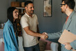 © La Famiglia - Joyful millennial spouses share a handshake with their therapist at the psychotherapist's office, symbolizing their progress and reconciliation after productive therapy sessions