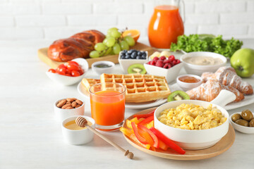 Wall Mural - Tasty breakfast. Scrambled eggs in bowl, cut bell pepper, honey and other food on light table