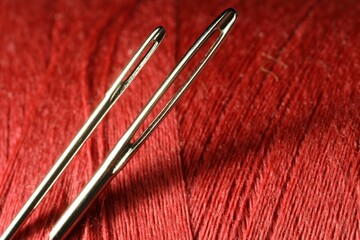 Wall Mural - Spool of red sewing thread with needles, macro view