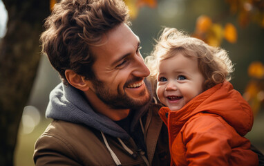 a man is holding a baby and smiling. the baby is wearing an orange jacket. scene is happy and warm