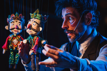puppeteer manipulating marionettes in a theater performance.
