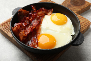 Sticker - Tasty bacon and eggs in dish on gray textured table, closeup