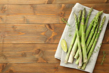 Wall Mural - Fresh green asparagus stems and lime on wooden table, top view. Space for text