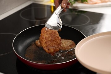 Wall Mural - Woman cooking schnitzels in frying pan on stove, closeup