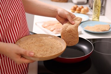 Canvas Print - Woman cooking schnitzel in frying pan on stove, closeup