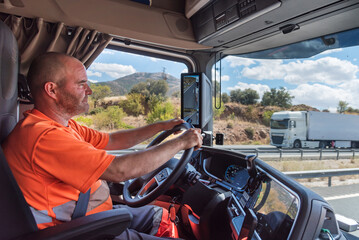 Trucker in the truck seat, concentrating on monotonous driving on a straight highway.