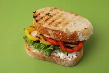 Tasty sandwich with grilled vegetables and cream cheese on green background, closeup