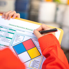 Wall Mural - extreme close-up at industrial worker'hand during verify on chemical and hazard material checklist, 