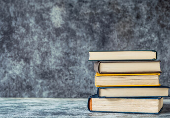 Aufkleber - Stack of books is sitting on a table, with copy space on grey wall textured background