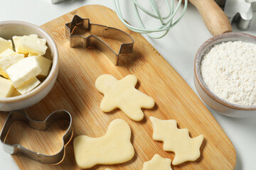 Wall Mural - Raw cookies, cutters, butter and flour on white table, closeup