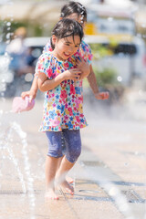 Poster - 夏の広場の噴水で水遊びをする女の子