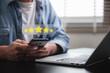 © IDOL'foto - Customer review good rating feedback concept, A person using a smartphone to leave a 5-star review, with emphasizing online feedback. testimonial and testimony, user comment and feedback for review.