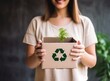 © Artsaba Family - Woman holding a cardboard box with a green recycling symbol. Global warming, planet pollution.