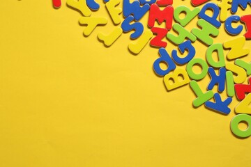 Poster - Learning alphabet. Magnetic letters on yellow background, flat lay. Space for text