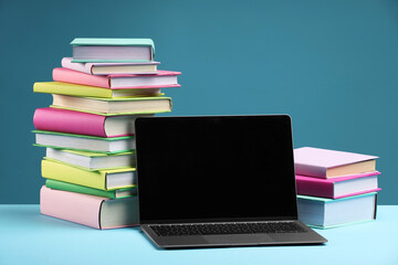 Wall Mural - Stacks of colorful books and laptop on light blue background