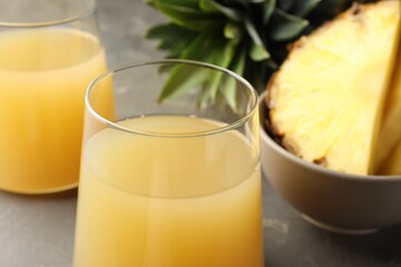 Wall Mural - Tasty pineapple juice in glasses and fruits on grey table, closeup