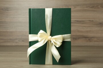 Wall Mural - Book with ribbon as gift on wooden table