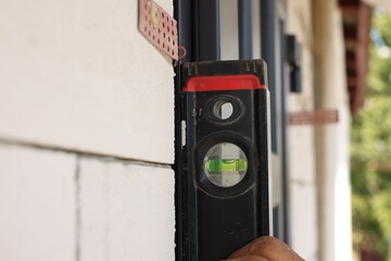 Sticker - Repairman with building level installing new door at home, closeup