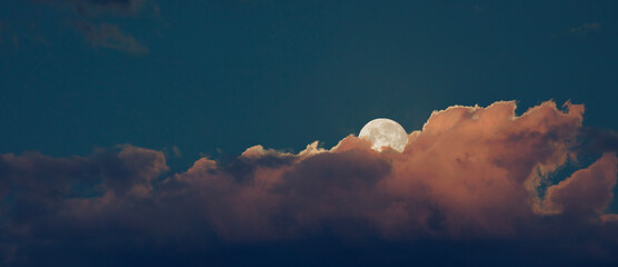 Wall Mural - moon rising behind an orange cloud bank