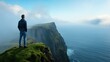 © angel_nt - A person stands on the edge of lush green cliffs, absorbing the serene beauty of the ocean and foggy landscape at dawn