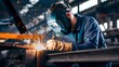 © FahemaRahman - Workers in engineering industrial production are welding metal materials using protective equipment such as fireproof gloves and welding helmets.