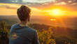 © Людмила Мазур - A man sits on a mountain top, looking out at the horizon. The sky is a beautiful mix of orange and pink hues, creating a serene and peaceful atmosphere. The man is lost in thought