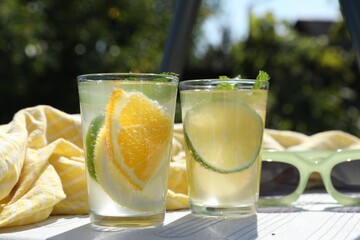 Canvas Print - Tasty cocktail in glasses and sunglasses near swimming pool outdoors