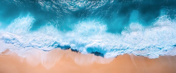 Aerial view of foamy waves crashing on a sandy beach.