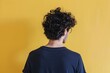 © BrandwayArt - Young man with curly hair stands against a bright yellow wall