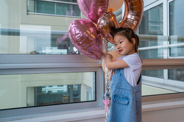 young girl is holding a pink balloon bouquet