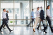 © Medical Works - business people walking in the corridor of an business center, pronounced motion blur, crowded bright modern light office movement defocused. office background busy. talking and rushing in the lobby.