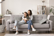 © fizkes - Smiling adolescent girl spend leisure time with beloved mother, relax on cozy sofa together, enjoy tender moments, hugging, smile, communicate. Happy family express love, care and good relationships