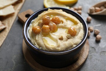 Wall Mural - Delicious hummus with olive oil and chickpeas in bowl on grey table, closeup