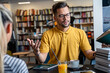 © Dorde - A Caucasian male and female student engage in a discussion over books in a library setting, beverages at hand, embodying a collaborative academic atmosphere.
