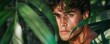 © Dalibor - Handsome man posing amidst lush green jungle leaves, looking mysterious.