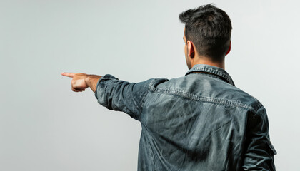 A man wearing a blue jacket is standing and pointing to the left. The background is neutral, drawing attention to his action and attire.