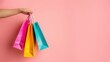 © Joyce - Hand holding shopping bags over plain background