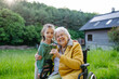 © Halfpoint - Granddaughter spending time with elderly grandma, picking wildflowers. Senior lady in wheelchair spending time in nature.