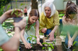 © Halfpoint - Portrait of students and female teacher at outdoor sustainable education class. Planting vegetable seedling, herbs in soil. Concept of experiential learning and ecoliteracy.