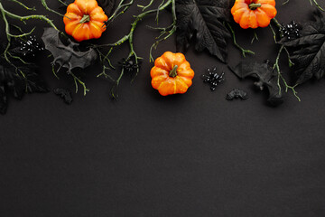 Wall Mural - Halloween decorations on dark background. Flat lay composition with pumpkins, branches with bats, spiders.