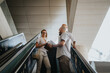 © qunica.com - Group of business professionals having a discussion while standing on an escalator in a contemporary office building