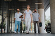 © qunica.com - Businesspeople walking in an outdoor meeting in an urban downtown area, showcasing professional interaction and collaboration with an office building background.