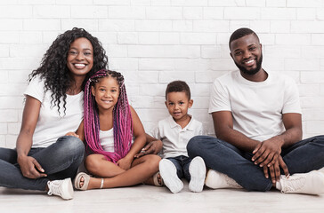 Wall Mural - Happy together. Portrait of joyful african american family with two little kids over white brick wall background