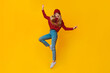 © Prostock-studio - Young happy winter woman showing dancing moves in the air over yellow background