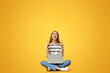 © Prostock-studio - Excited teen girl with laptop pointing upwards at free space on yellow studio background