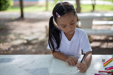 young girls are sitting at a table with markers and coloring books.