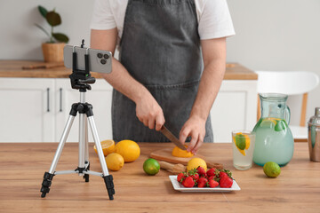 Wall Mural - Young man recording video of him making homemade lemonade in kitchen