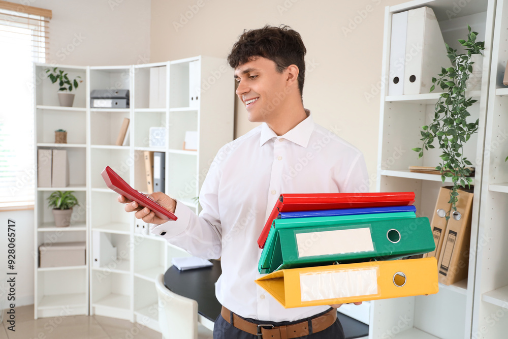 Male accountant holding folders stack and calculator in office