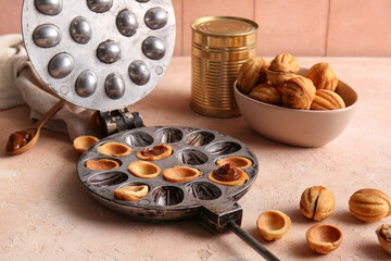 Baking form with tasty walnut shaped cookies and tin can of boiled condensed milk on color table