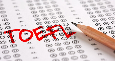 Wall Mural - Close up view of an exam paper with the word TOEFL test of English as a Foreign Language and a pencil.